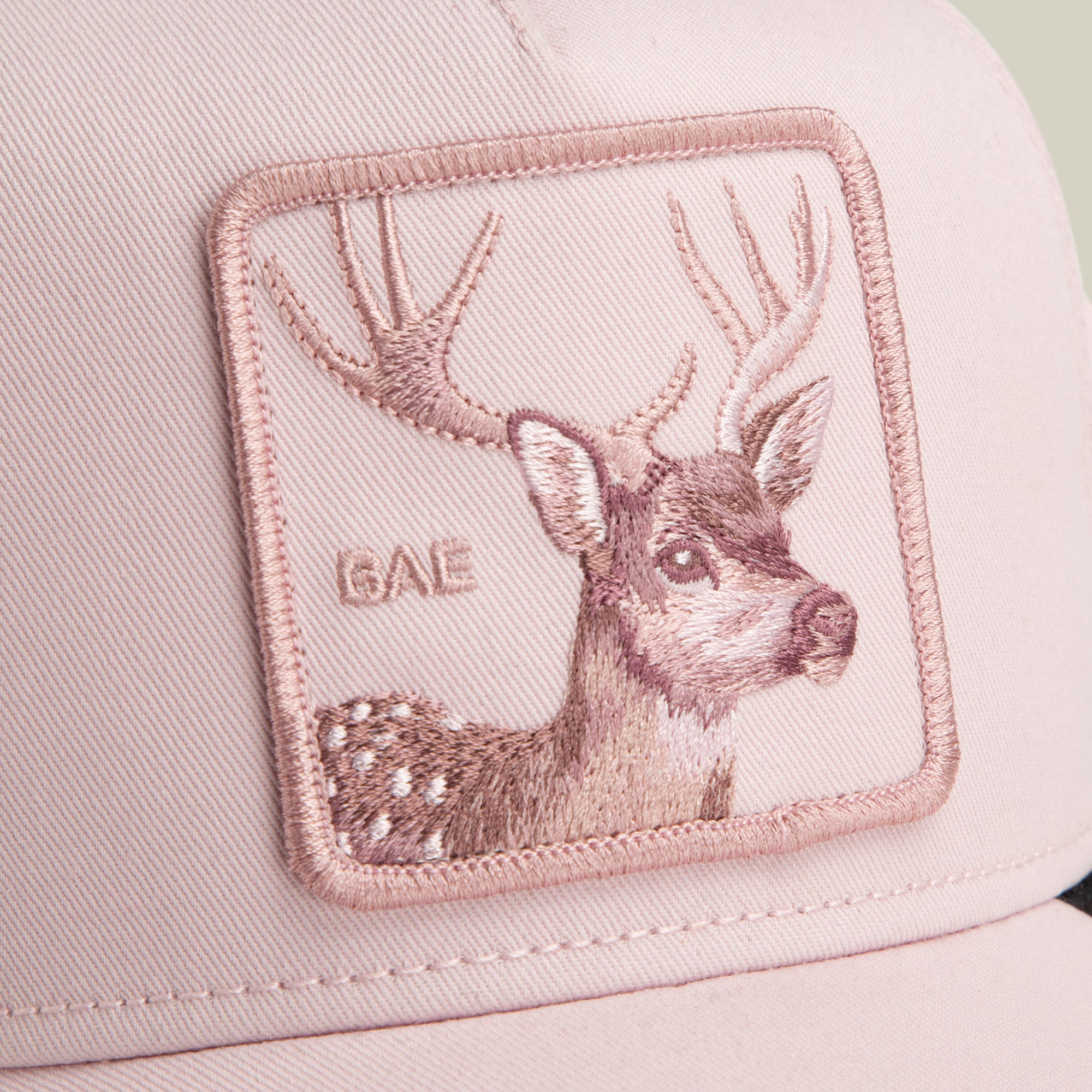 Close-up of the Mirage Bae pink baseball cap by Goorin Bros., featuring a deer patch with antlers and "BAE" stitched beside it—a playful yet classic accessory.