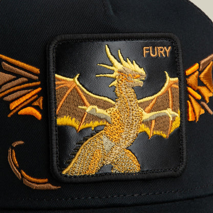 Goorin Bros. Wings Fury trucker hat featuring a gold embroidered dragon with spread wings on a black fabric patch, displayed as a close-up product shot.