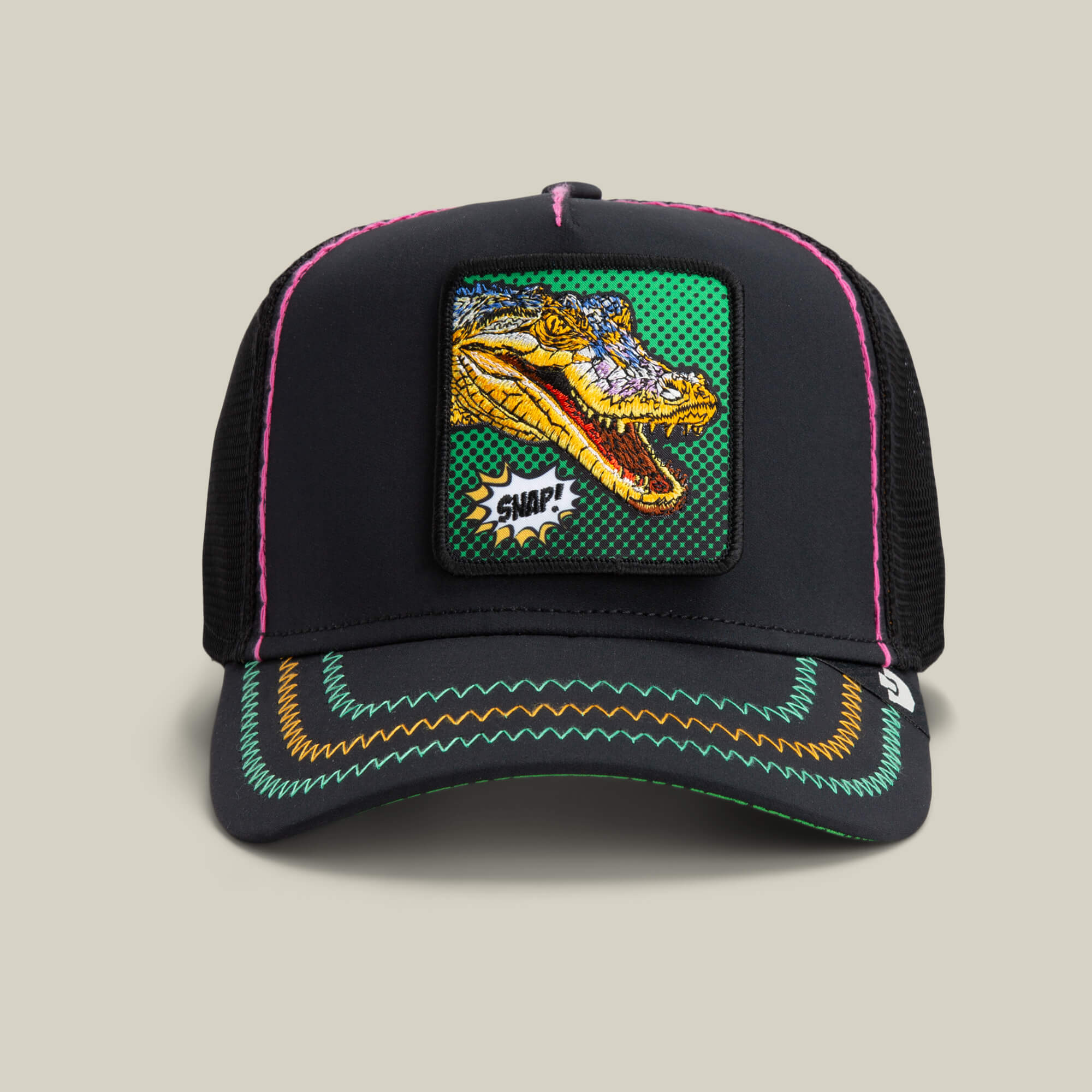 The Goorin Bros. "Crackle and Pop, Brother" trucker hat in VOID features a colorful embroidered dinosaur patch and neon stitching on the brim, bringing a bold Pop Art touch.