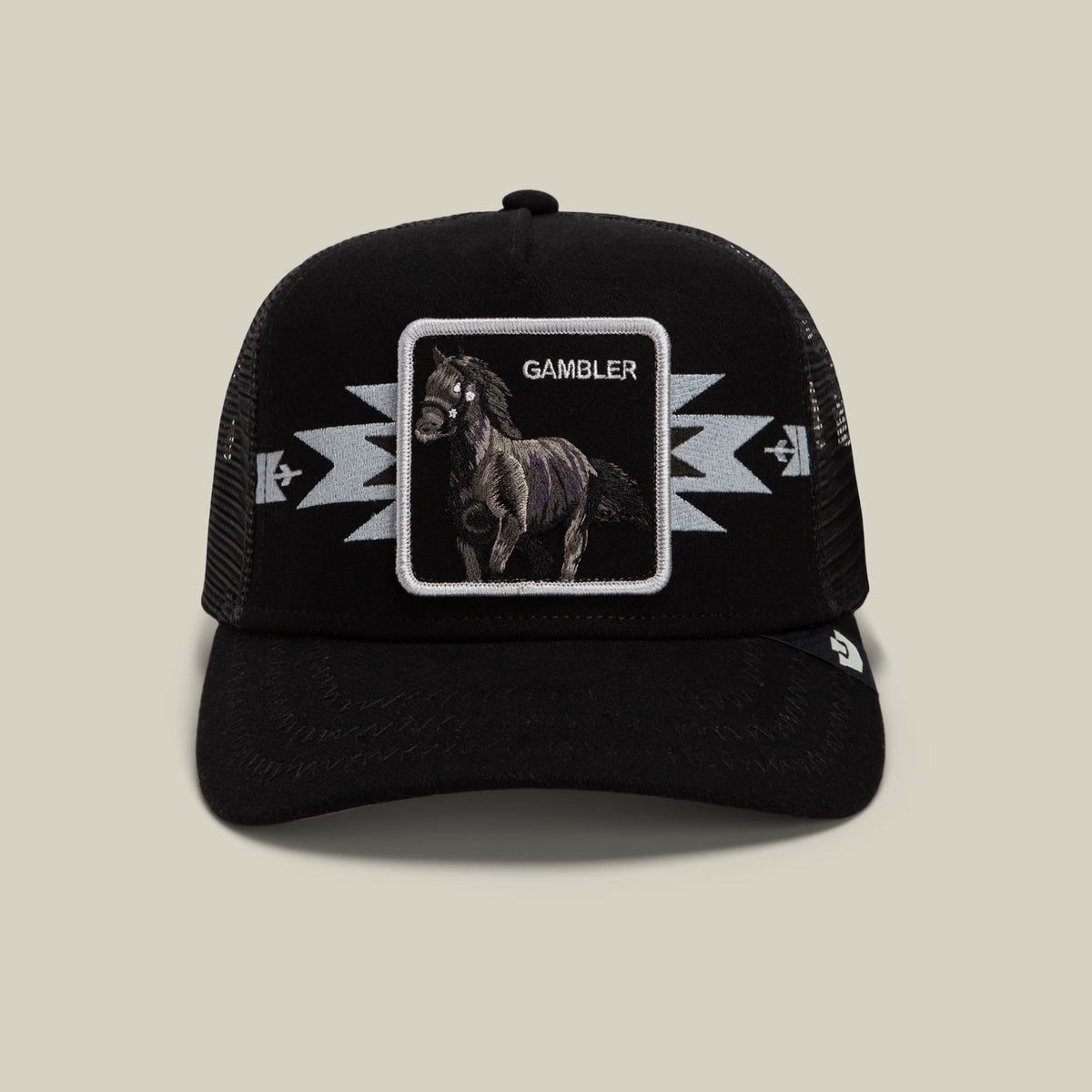 The Goorin Bros. Canyon Gambler black trucker hat features a mesh back, embroidered horse patch with "Gambler" text, and lightning bolt designs on the front panel, displayed against a neutral studio background.