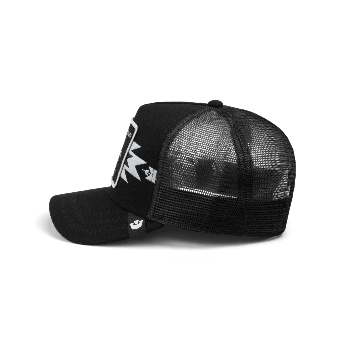 The Canyon Gambler by Goorin Bros is a black mesh trucker hat with a structured front panel and white logo embroidery, shown in a studio product shot against a dark background.