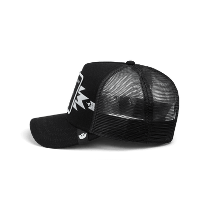 The Canyon Gambler by Goorin Bros is a black mesh trucker hat with a structured front panel and white logo embroidery, shown in a studio product shot against a dark background.