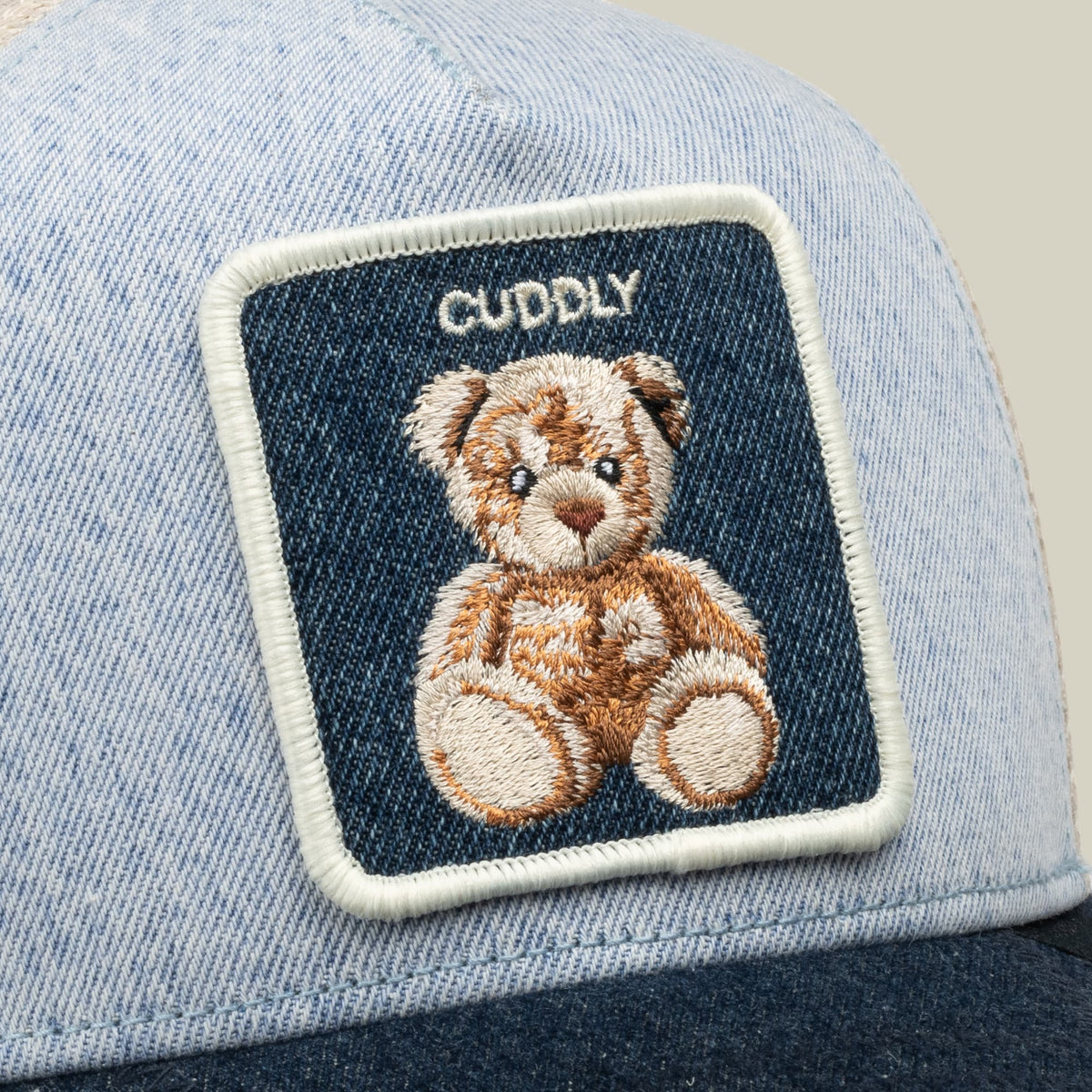 The Goorin Bros. Denim Cuddly baseball cap features a light blue and navy blue colorblock design with an embroidered teddy bear patch on the front.