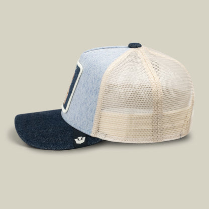 The Goorin Bros. Denim Cuddly trucker hat features a color-blocked design with light blue denim front, cream mesh back, and dark navy bill, displayed in a studio product shot.