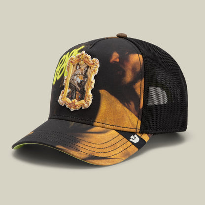 The Coming of Saint Matthew trucker hat by Goorin Bros features a black mesh back with a gold and brown printed front panel, ornate gold embroidered patch, and small logo detail on the bill.