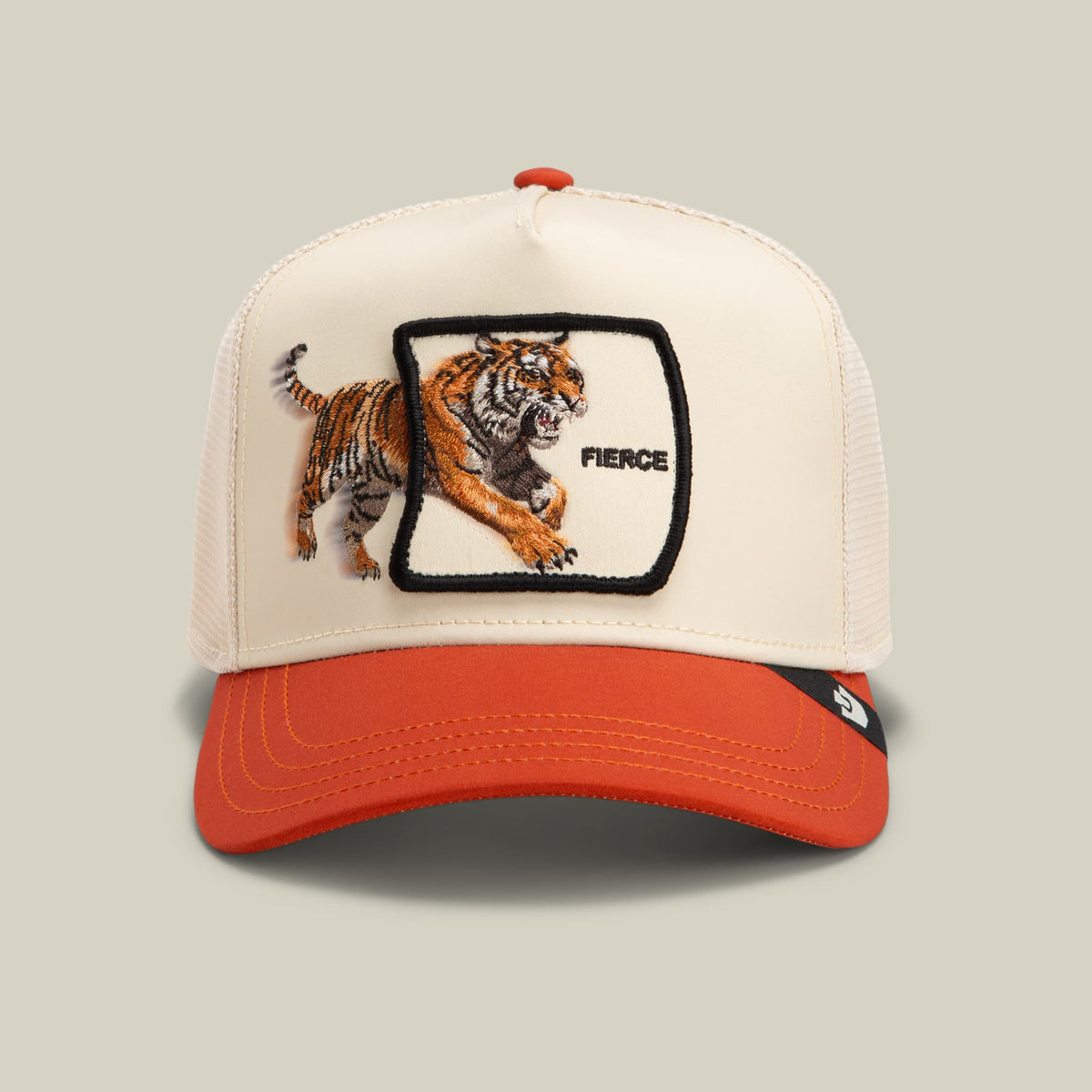 The Goorin Bros. Migration Fierce trucker hat features a cream mesh back and red-orange bill with an embroidered tiger patch and "Fierce" text on the front panel, displayed against a neutral background.