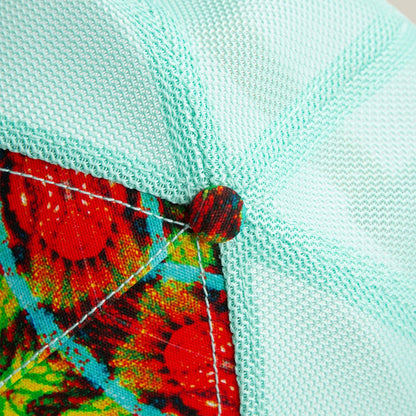 Close-up of the Goorin Bros. Magic Eye hat, featuring textured light blue mesh, a colorful button, and patterned seam accents that create subtle optical illusions.