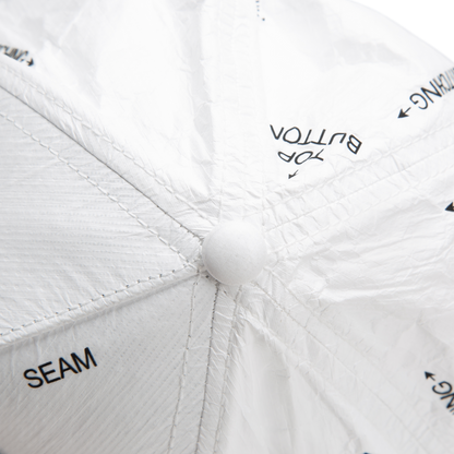Close-up of the top of a white K.I.S.S. hat by Goorin Bros., showing labeled sections like SEAM and TOP BUTTON, plus visible stitching details.