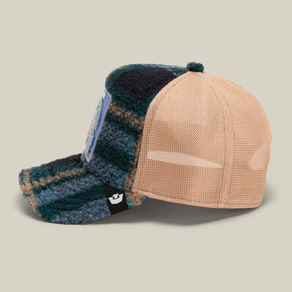 Side view of the Goorin Bros. "Double Stuffed - Bunny" trucker hat featuring a green and blue plaid fleece front, beige mesh back, curved bill, adjustable snapback, and a small black tag on the side. The front is finished with a plush chenille bunny patch for an extra touch of charm.