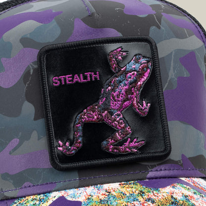 A close-up of the Goorin Bros. "Silent But Deadly" cap reveals a camouflage design with a black patch, an embroidered purple frog, and STEALTH in purple—ideal for fans of the Frogs of War collection.