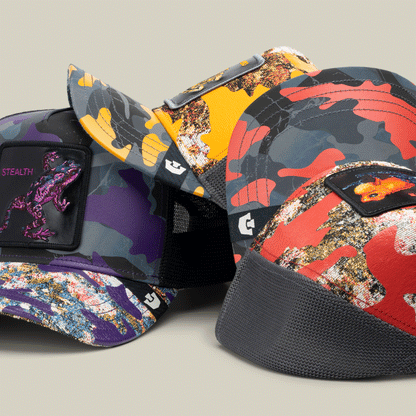 Four Secret Service camouflage baseball caps by Goorin Bros.—purple, yellow, gray, and bold red trucker—each with a dinosaur patch on the front, are displayed against a neutral background.