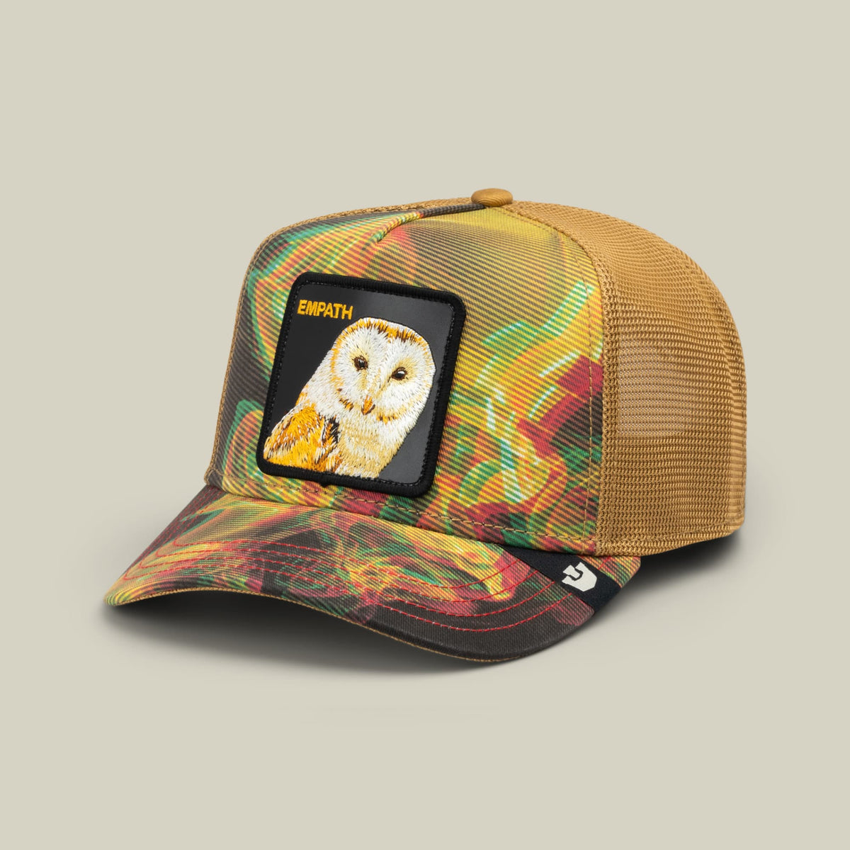The Goorin Bros. Androids Dream trucker hat features a colorful multicolor plaid front panel with a mesh back in tan, topped with an embroidered owl patch labeled EMPATH on a black background.
