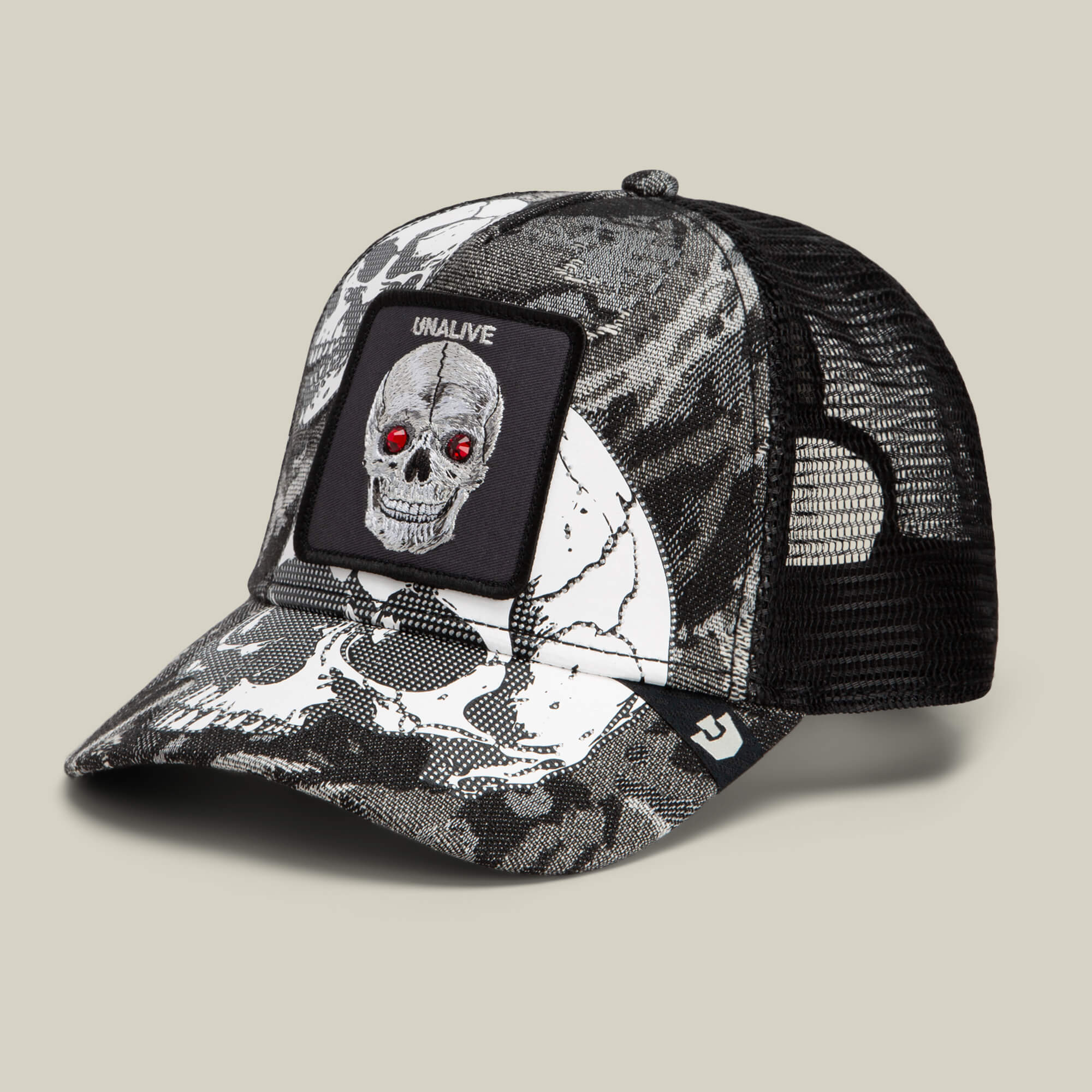 The Bone Head Unalive trucker hat by Goorin Bros. features a bold black and white skull print with red gem-like eyes, a breathable mesh back, and a signature UNALIVE patch.