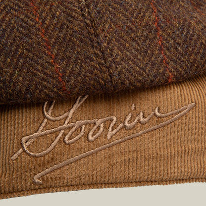 Close-up of the Goorin Bros. Frazier Lake cap, featuring brown tweed, tan corduroy ear flaps, and "Yours" embroidered in cursive on the corduroy section.
