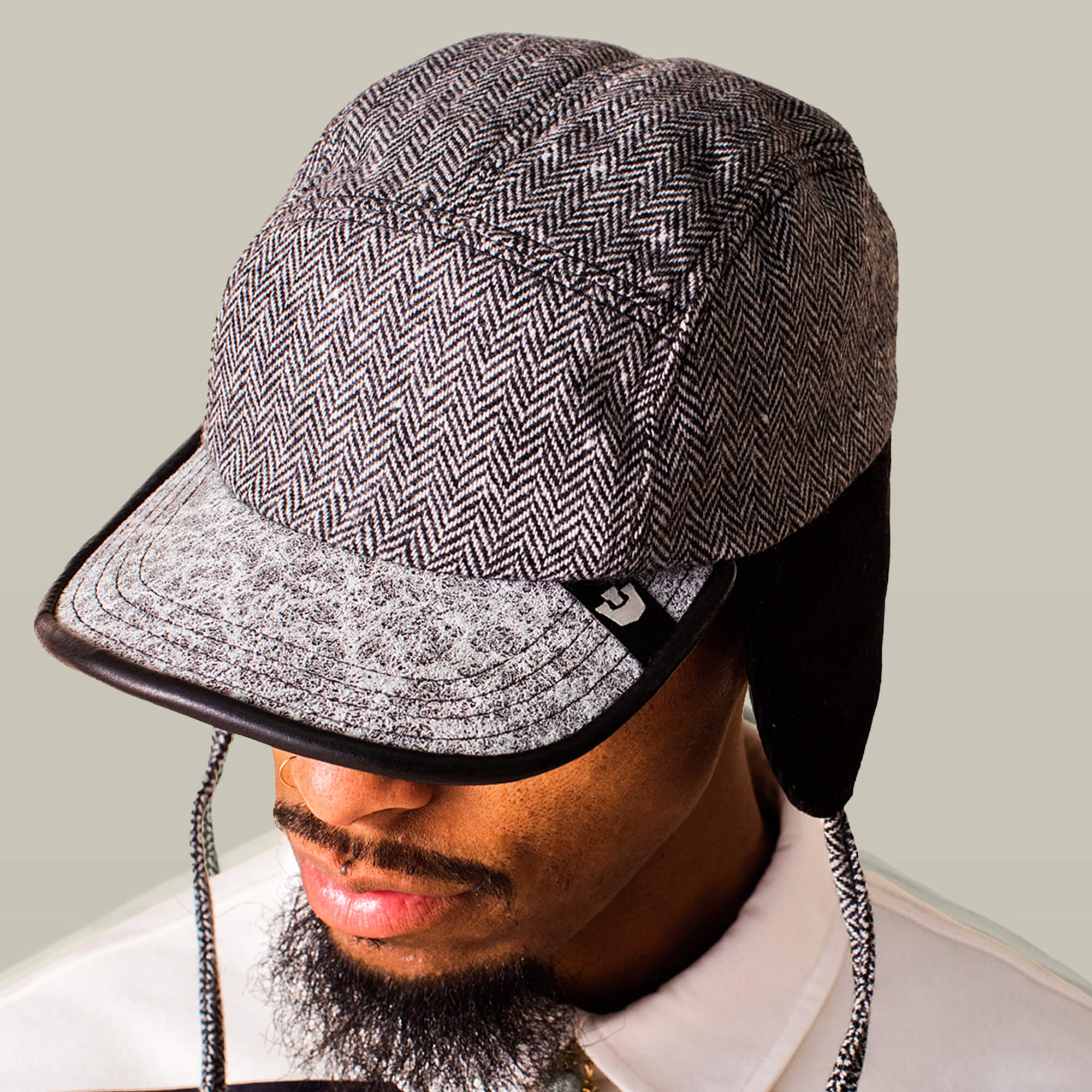 A man in a white collared shirt wears the Goorin Bros. Frazier Lake, a grey herringbone-patterned wool trapper cap with ear flaps and a textured visor.