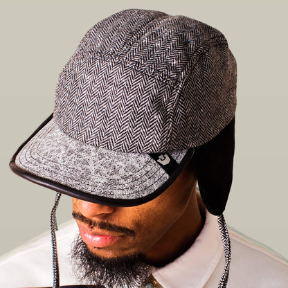 A man in a white collared shirt wears the Goorin Bros. Frazier Lake, a grey herringbone-patterned wool trapper cap with ear flaps and a textured visor.