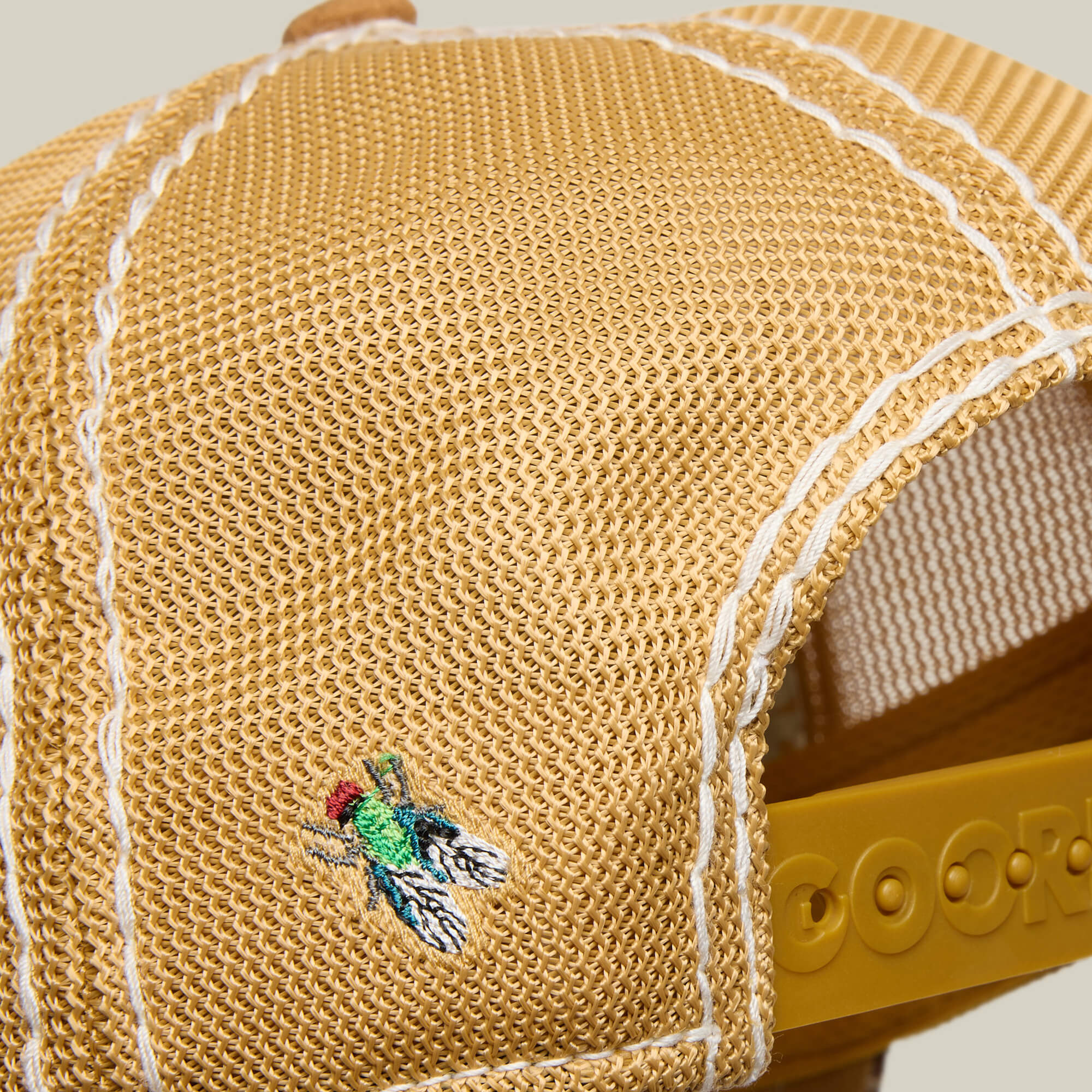 A close-up of the Goorin Bros. Tijuana Special: a yellow mesh baseball cap with white stitching and an embroidered green and black Tijuana Special fly near the back.