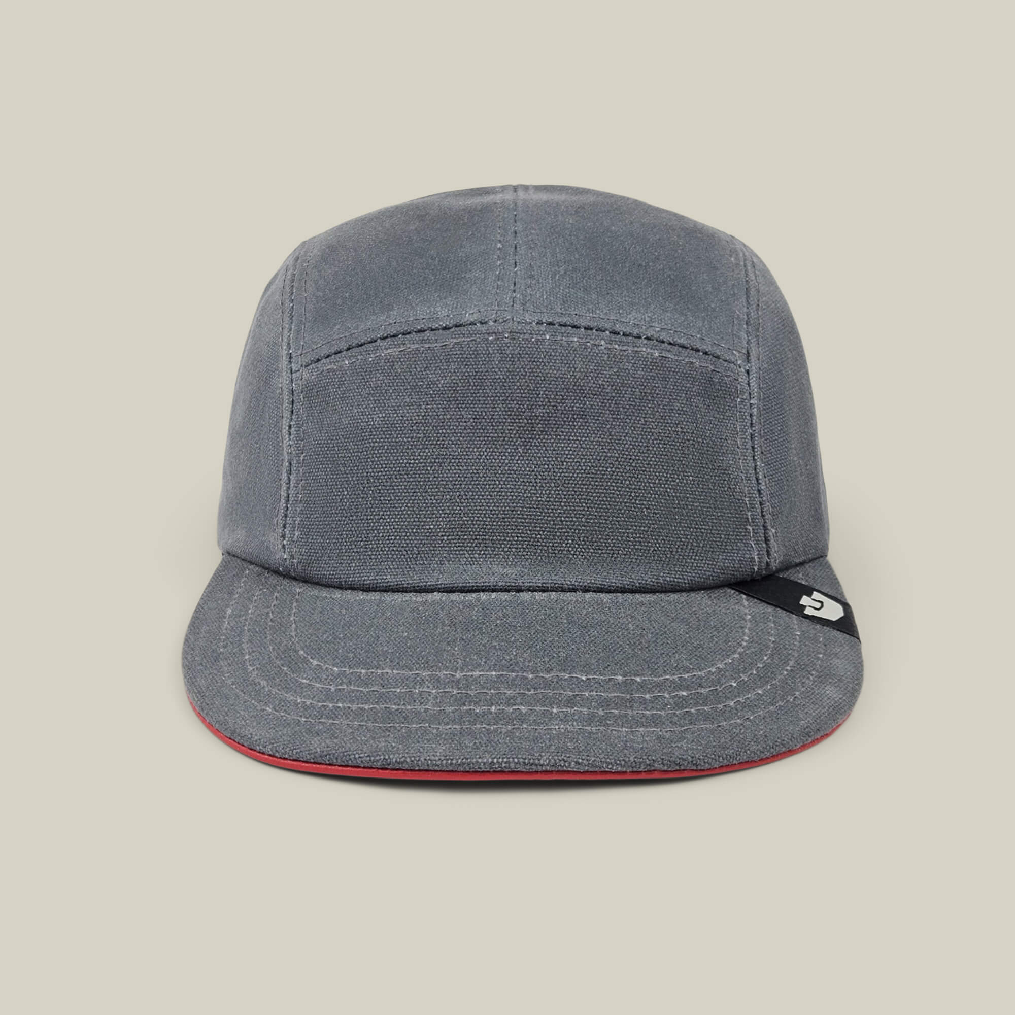 The North Boulder by Goorin Bros. is a gloss gray 5-panel camp cap with visible stitching, a slightly curved brim, and a small black tag on the left side, hand cut and sewn for quality, shown on a plain beige background.