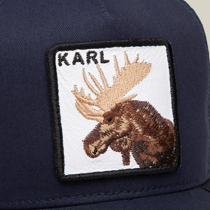 Close-up of the Goorin Bros. Karlsson Moose cap in navy blue, featuring a rectangular patch with an embroidered moose and "KARL" at the top—an homage to hockey legends.