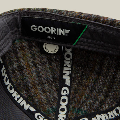 Close-up of the inside of a Goorin Bros. Cozy Tailored Baseball hat, showing the brand label and patterned inner lining with repeating GOORIN text on the hat band in a muted colorway.