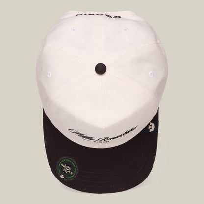 The Goorin Bros. Mildly Remarkable Script hat features a white crown, black brim, classic script embroidery on the front, and a round authenticity sticker on its low pro fit brim.