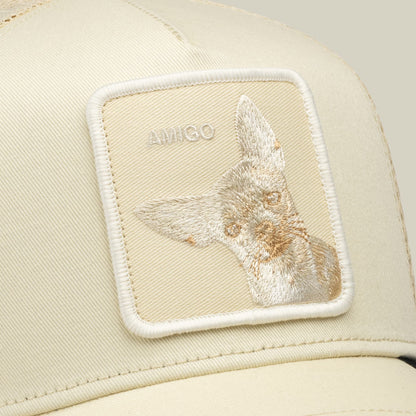 The Goorin Bros. Tonal Amigo cream trucker hat features an embroidered animal patch on the front panel against a neutral beige background in a close-up studio shot.