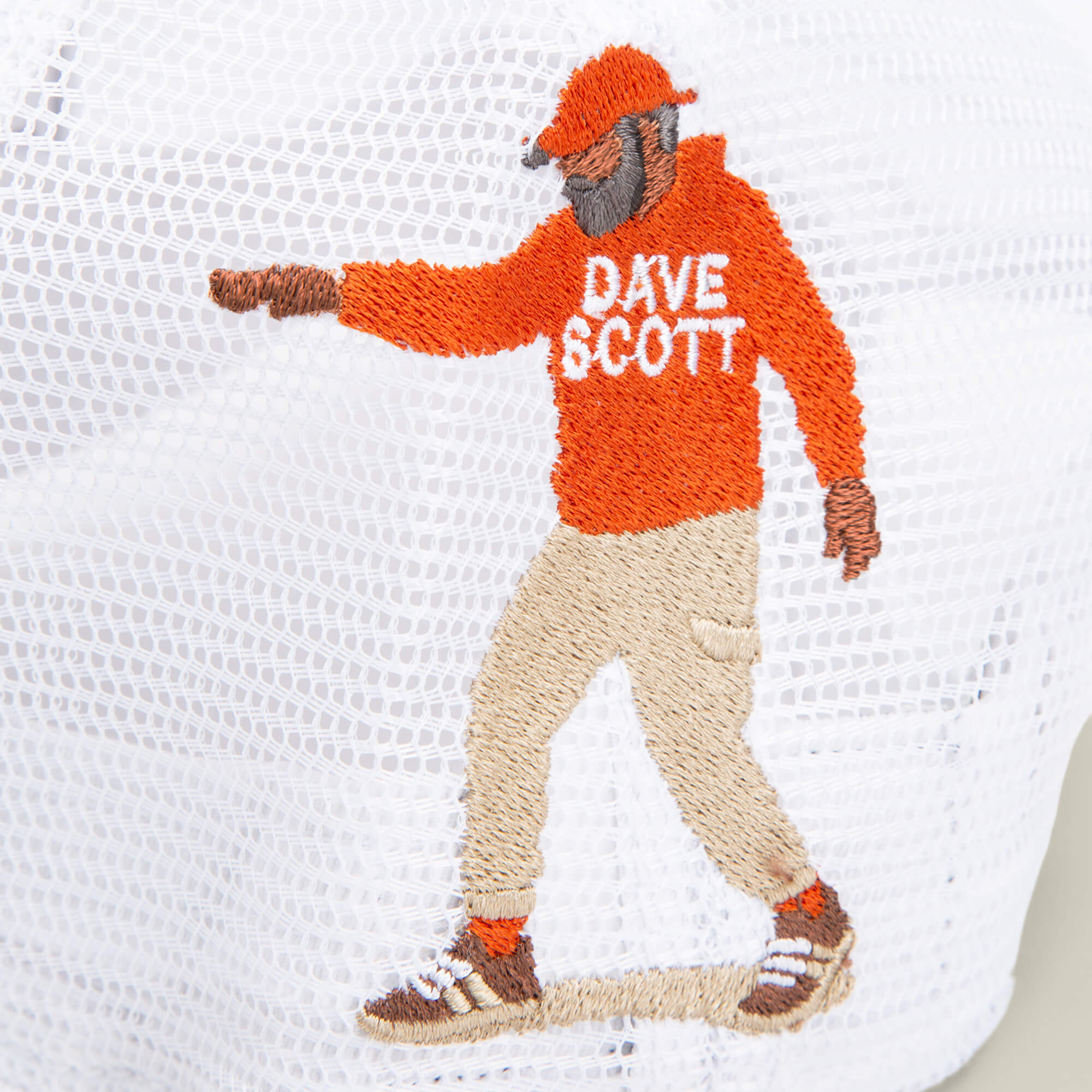 Depicted in a walking pose on white mesh, the embroidered figure wears a red hoodie labeled "Dave Scott," tan pants, and sneakers. Part of Goorin Bros.’ Dave Scott My Beautiful Lion collection.