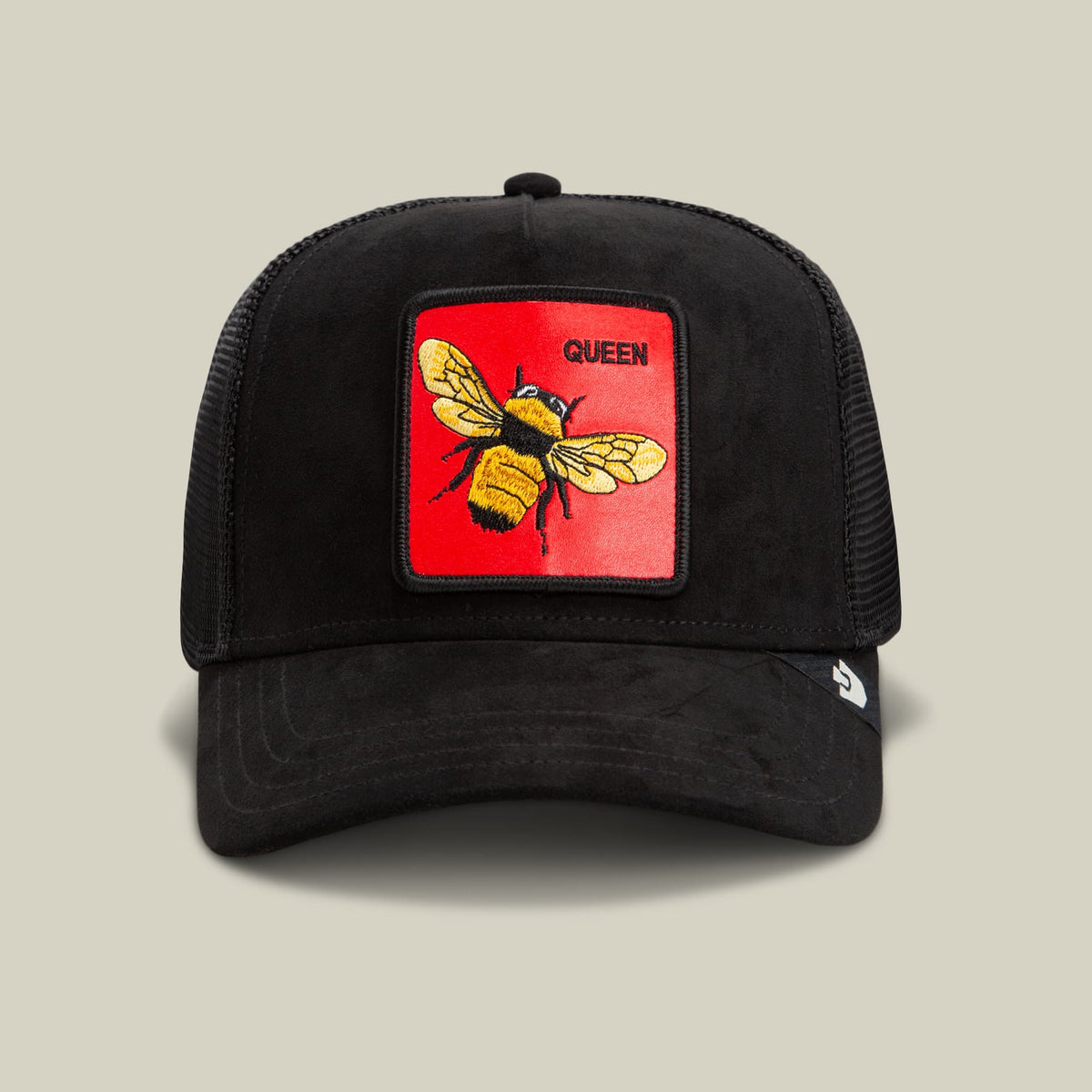 The Goorin Bros. Regina Rossa is a black trucker hat with mesh panels and a red embroidered patch featuring a yellow and black bee with the word Queen, displayed against a neutral studio background.