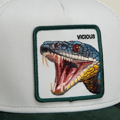 The Goorin Bros. Suede Snake trucker hat features a white front panel and green back with an embroidered patch of a vicious snake with its mouth open, detailed in blue, red, and yellow thread.
