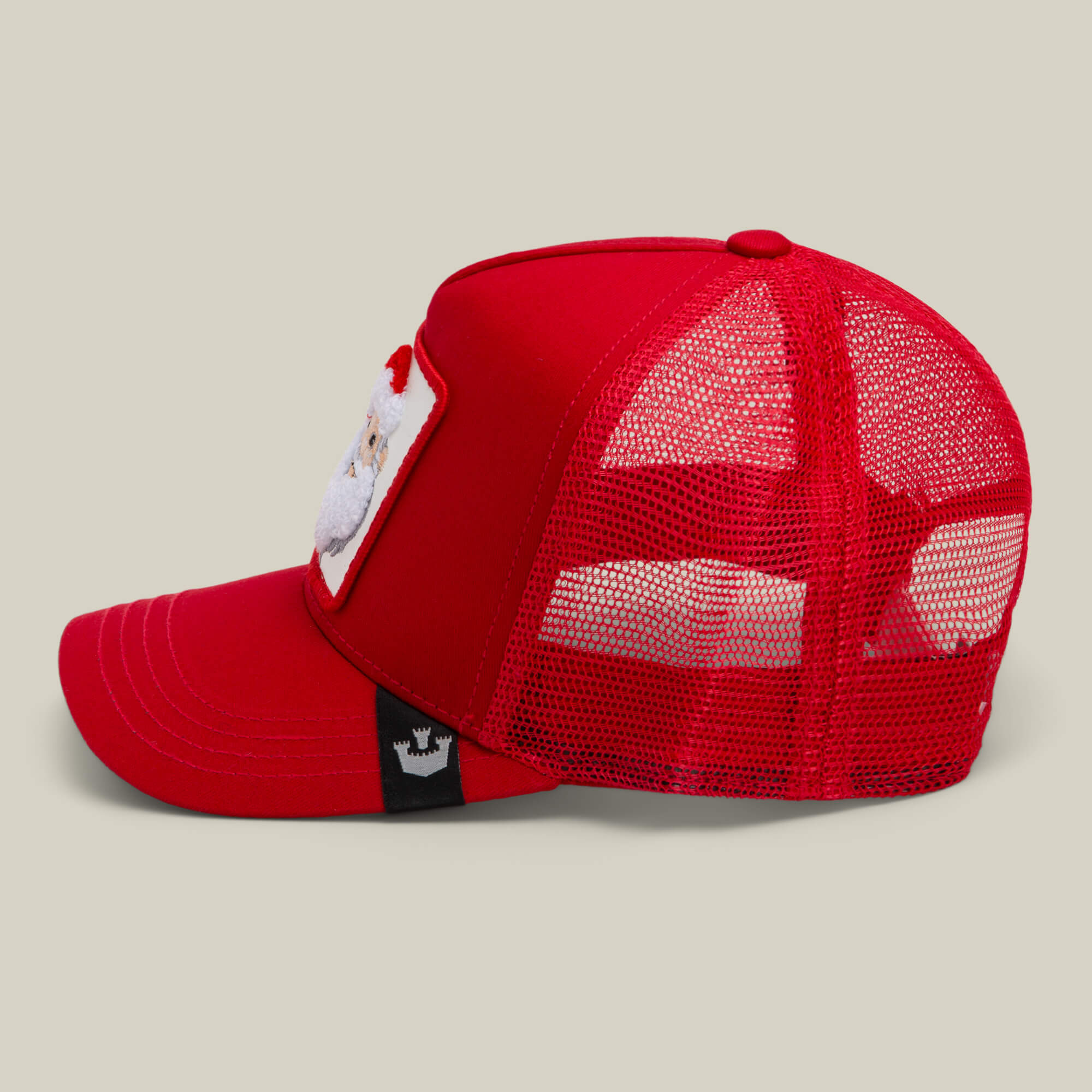 The Goorin Bros. Mr. Claus cap is a red mesh trucker hat with a Santa patch on the front panel, shown from the side against a plain background—great for festive holiday style.