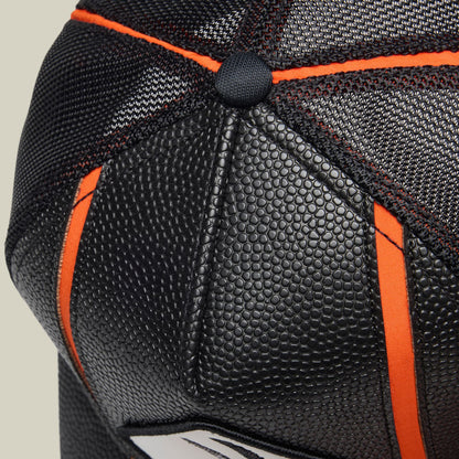 The Goorin Bros. Know Ball baseball cap features black breathable mesh with orange fabric accents and a textured black rubber patch detail on the crown, shown in a close-up product shot.