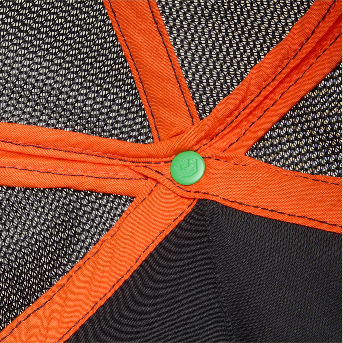 The Know Ball by Goorin Bros features a structured design with black mesh fabric panels, bright orange binding and straps, and a green button detail at the center, displayed in a flat lay close-up shot.