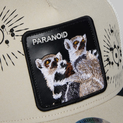 The Goorin Bros. G-Anon trucker hat features a cream canvas crown with black mesh back and an embroidered paranoid patch depicting two wide-eyed lemurs with golden eyes on a black background.