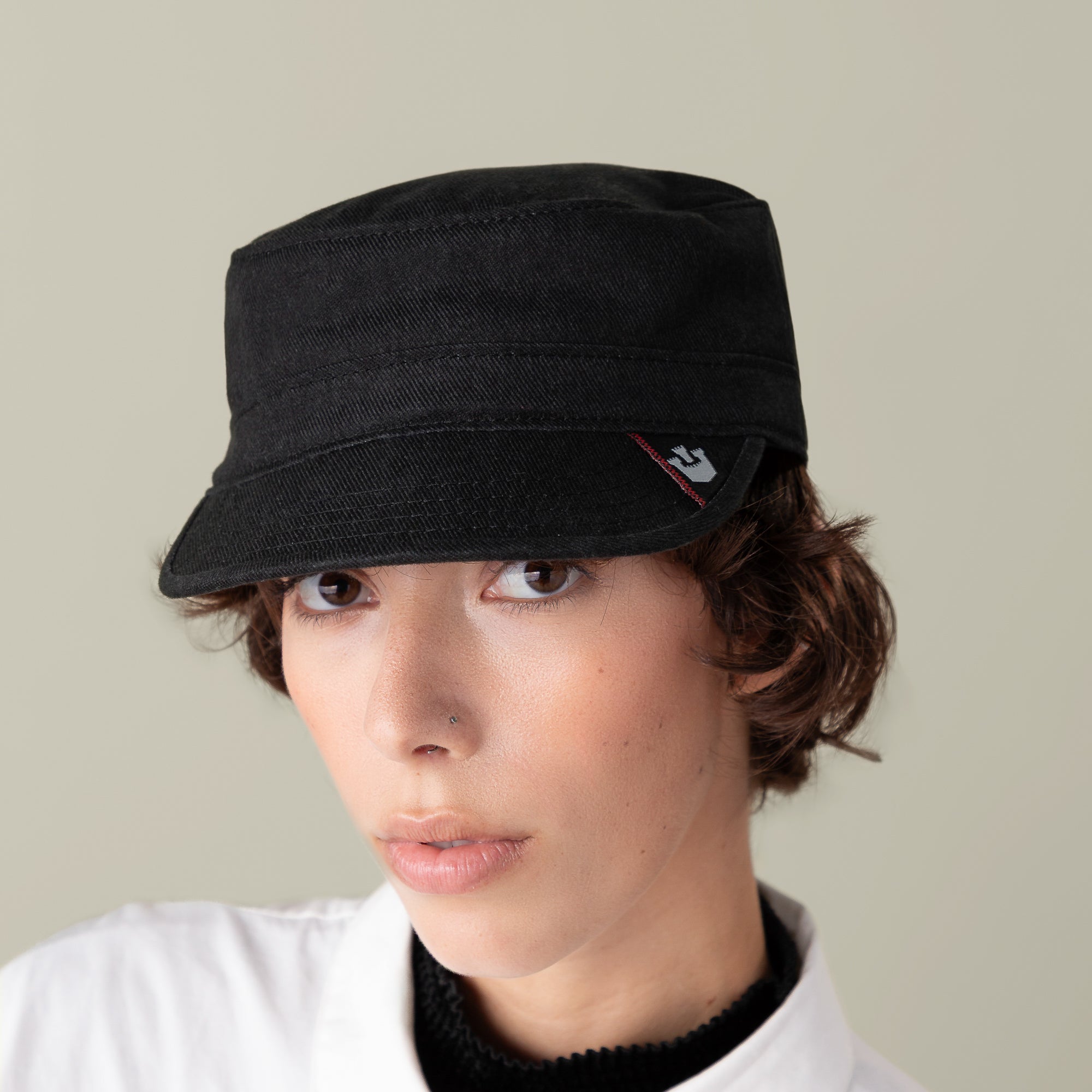 A person wears the Goorin Bros. "Home at Last" stylish black cap with a small side logo and a white collared shirt, set against a neutral background.