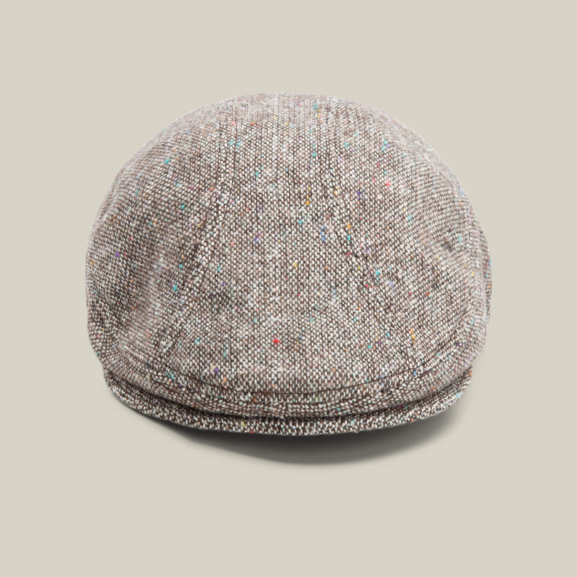 The Gibbins cap by Goorin Bros., in the color GROUND, features a speckled tweed design ideal for men's fashion and is showcased against a plain beige background.