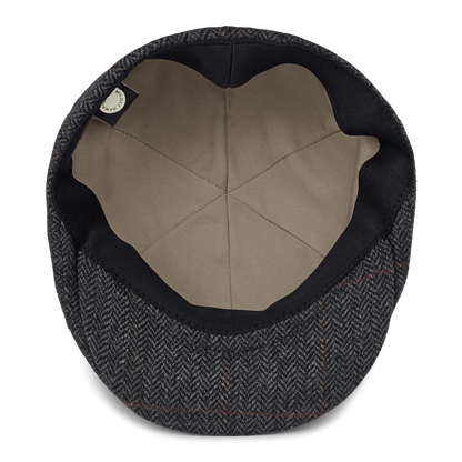 The Harry Bones flat cap by Goorin Bros. is shown from above, displaying a beige inner lining and a dark herringbone-patterned wool exterior—classic headwear thoughtfully made in the USA.