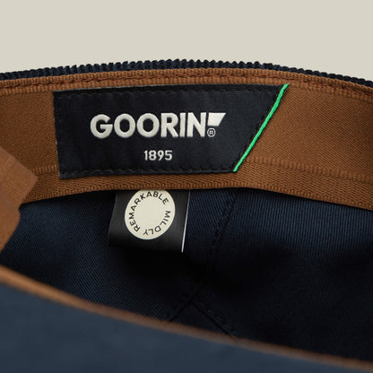 Close-up of a Cozy Low Profile interior by Goorin Bros., featuring a black GOORIN 1895 label and a white REMARKABLY MADE tag stitched to brown and navy blue fabric—an ideal everyday flatcap detail.