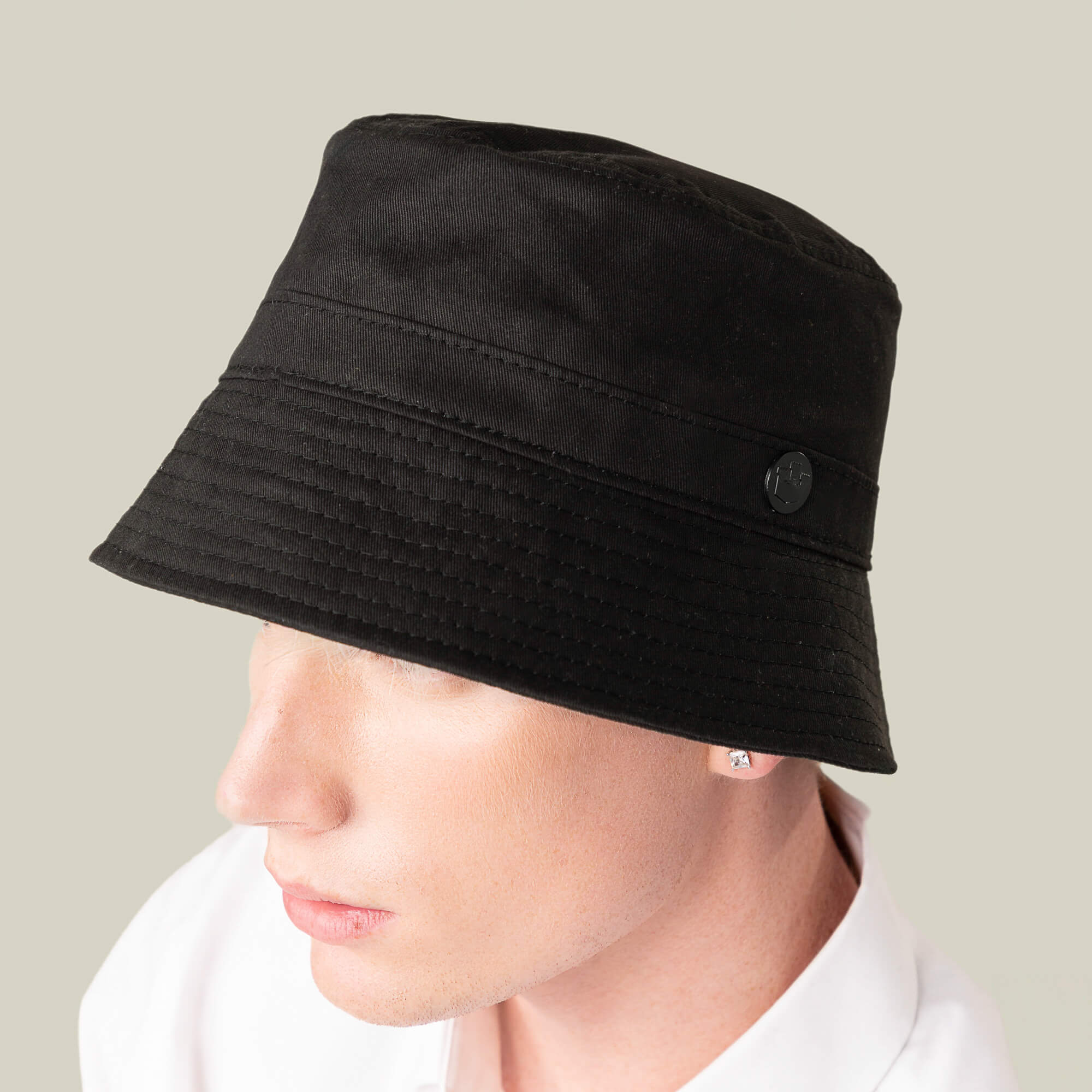 A person wearing the Goorin Bros. Odyssey Bucket, a solid black cotton hat, and a white shirt is seen from the side against a neutral background.