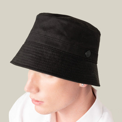A person wearing the Goorin Bros. Odyssey Bucket, a solid black cotton hat, and a white shirt is seen from the side against a neutral background.