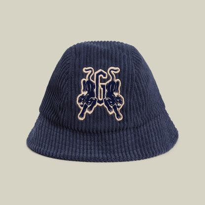 The Yes Coach bucket hat by Goorin Bros. is a navy corduroy style with bold ribs and mirrored twin panther patches embroidered on the front.