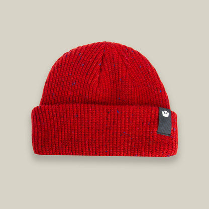 The Goorin Bros. "No Comply" beanie is a warm, red knit hat with a folded brim and a small black tag on the right side, shown on a light beige background.