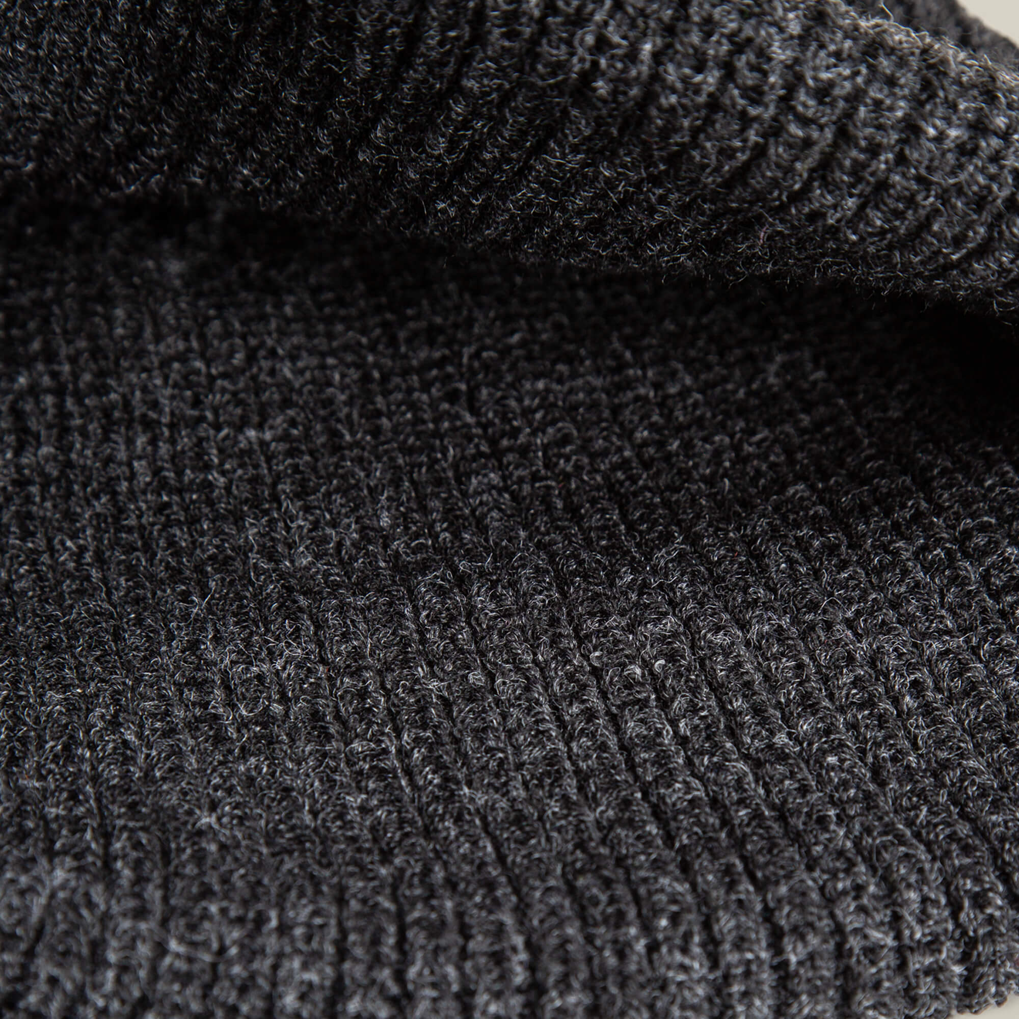 Close-up view of the black ribbed knit fabric from The Black Panther Beanie by Goorin Bros., highlighting its detailed texture and stitching pattern.