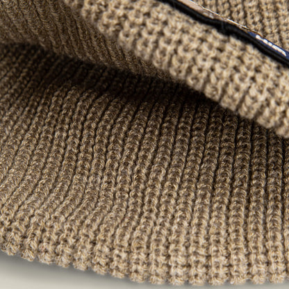 Close-up view of brown ribbed knit fabric with visible stitches, highlighting the cozy texture and details of The Him Beanie by Goorin Bros.—a stylish way to add warmth and flair to your look.
