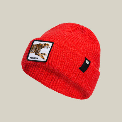 The Nonstop Beanie by Goorin Bros. is a red knit winter hat featuring a patch with a running cheetah labeled "NONSTOP" and a small black rectangular tag with a white graphic.