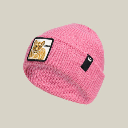 The Queen Beanie by Goorin Bros. is a pink knit hat with a lioness and "QUEEN" patch on the front, plus a small black label on the side.