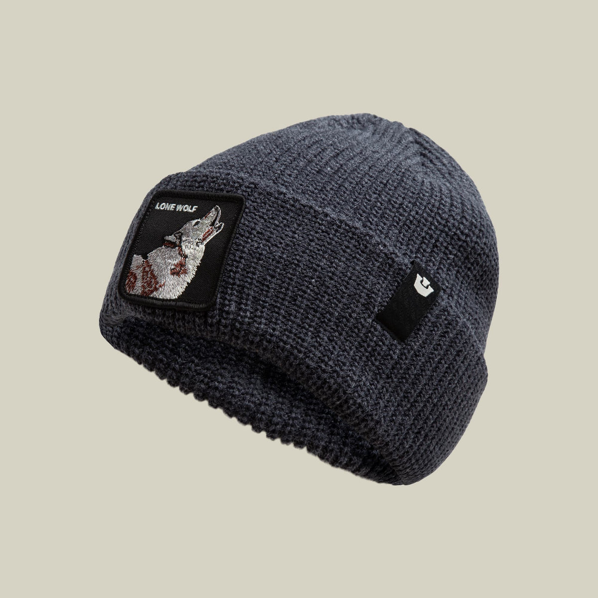 The Lone Wolf Beanie by Goorin Bros is a dark charcoal ribbed knit beanie featuring an embroidered wolf patch on the front and a small brand logo on the side, displayed against a neutral background.