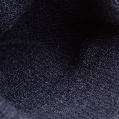 Close-up of dark navy knit fabric from The Top Beanie by Goorin Bros., showcasing its textured, woven pattern and fibers—beautifully accented with a signature St. Bernard patch.