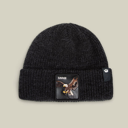 The Savage Beanie by Goorin Bros. in VOID features a folded brim, eagle patch labeled SAVAGE, and a side tag. This warm, rugged knit beanie brings bold style to any outfit.