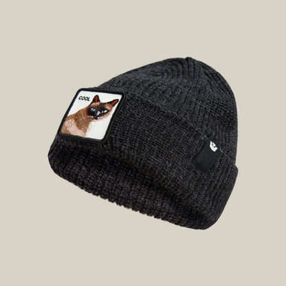 The Cool Beanie by Goorin Bros. is a dark black ribbed knit beanie featuring a patch with a cat and "COOL"—ideal for streetwear style. Shown on a plain, light background.