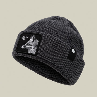 The Silver Beanie by Goorin Bros is a charcoal gray ribbed knit beanie featuring a black patch with a silver fox design and text on the front, displayed against a neutral background.